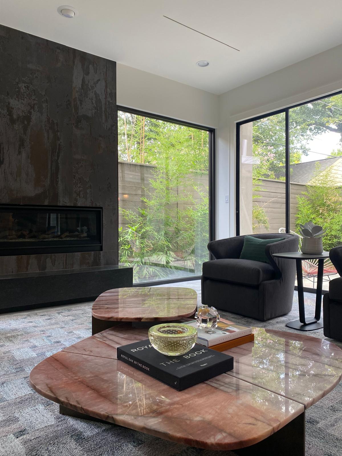 Wider living room view with a metal fireplace wall, pink marble tables and garden, Montrose