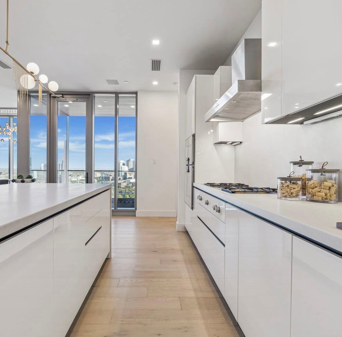 Galley view of the white kitchen with light oak floors, The Residences at The Allen